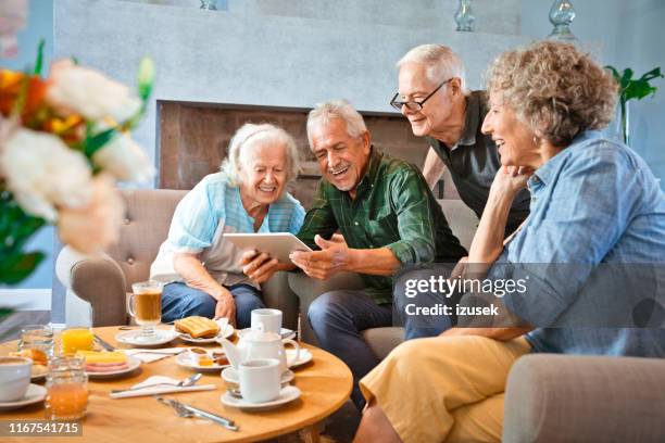 amici anziani sorridenti che condividono tablet digitale - social gathering foto e immagini stock