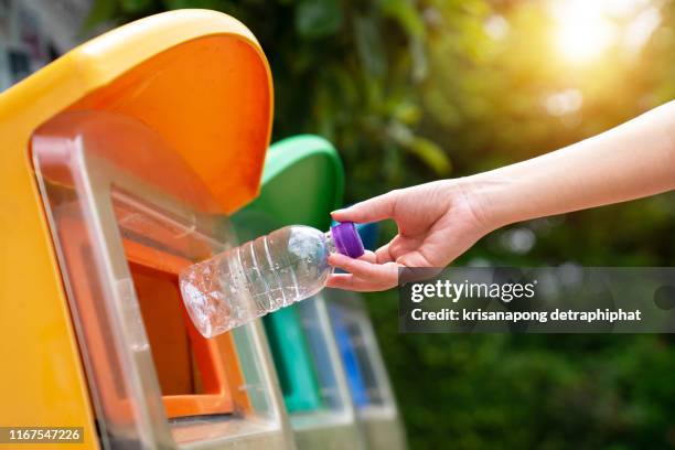 world environment day concept. woman hand holding and putting plastic bottle waste into garbage trash. - recycling fotografías e imágenes de stock