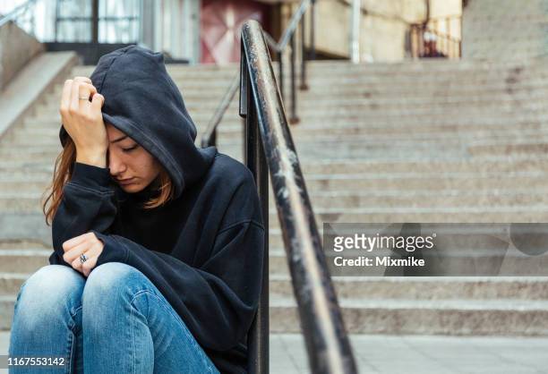 depressive junge frau sitzt auf der straße - victim stock-fotos und bilder