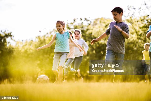 groep kinderen spelen met een bal in het park - club de fútbol stockfoto's en -beelden