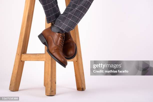 foot hanging from wooden stool with brown shoes with a white background - brown suit 個照片及圖片檔