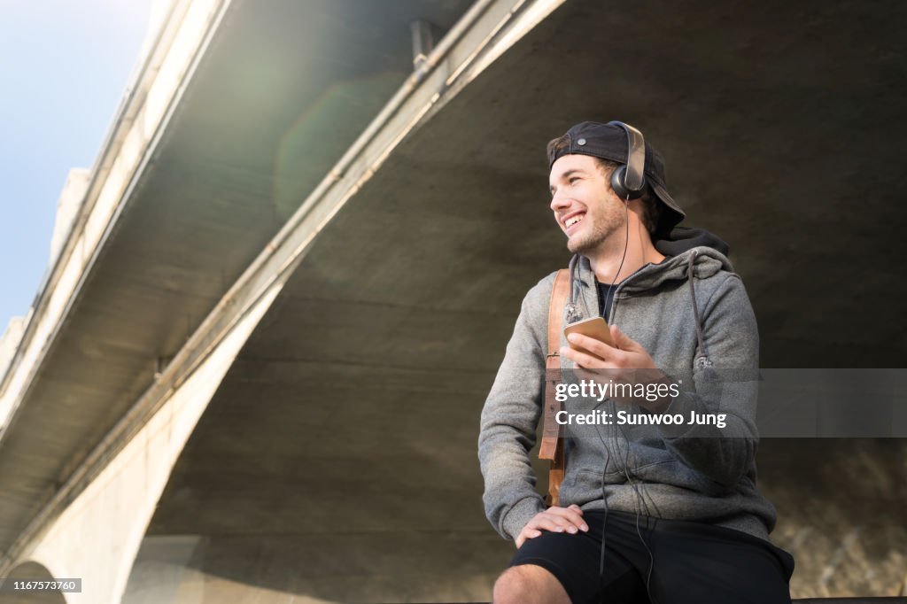 Male athlete talking on phone underpass at sunset