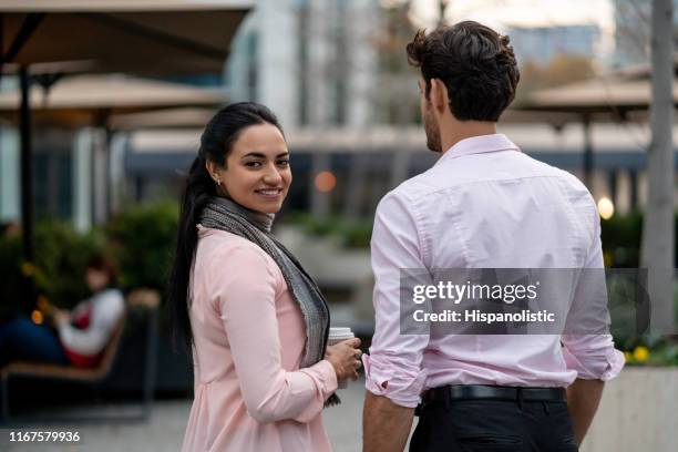 mooie zakenvrouw genieten van een kopje koffie met collega terwijl geconfronteerd met camera glimlachend - facing camera professional outdoor stockfoto's en -beelden