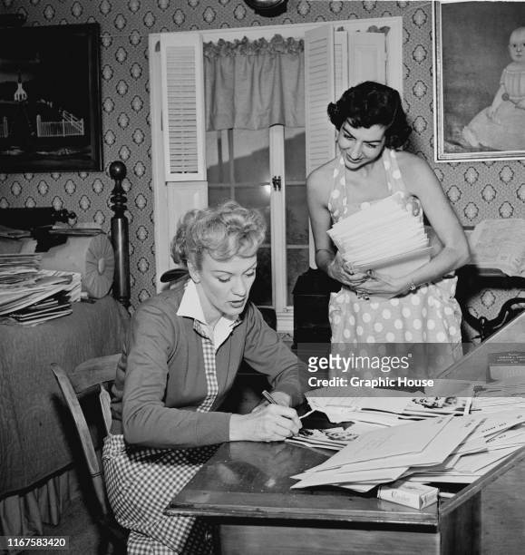 American actress Eve Arden signs some headshots, circa 1960.