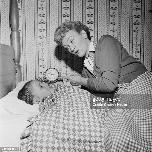 American actress Eve Arden puts one of her daughters to bed, circa 1960.