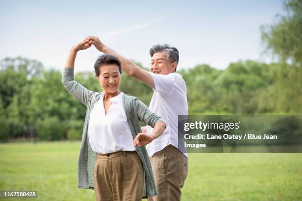 happy senior chinese couple dancing on grass - free pictures ballroom dancing stock pictures, royalty-free photos & images