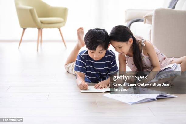 happy chinese sibling studying in living room - barefoot feet up lying down girl stockfoto's en -beelden
