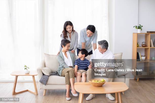 happy chinese family relaxing on sofa - grandmas living room photos et images de collection