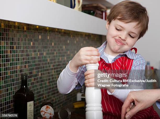 toddler boy grinding pepper in kitchen - pepper mill stockfoto's en -beelden