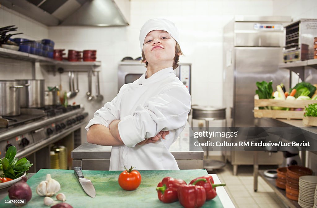 Boy chef with vegetables in kitchen