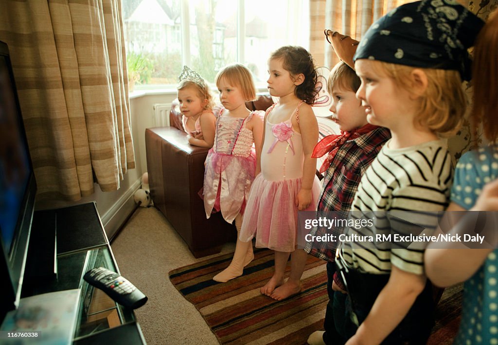 Children in costumes watching television