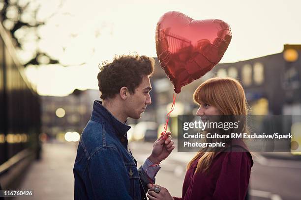 couple walking with heart-shaped balloon - valentine stock-fotos und bilder