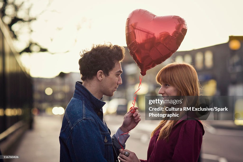 Couple walking with heart-shaped balloon