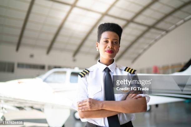 porträt des flugzeugpiloten in einem hangar und blick in die kamera - female pilot stock-fotos und bilder