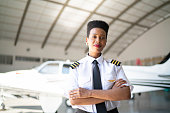 Portrait of airplane pilot in a hangar and looking at camera