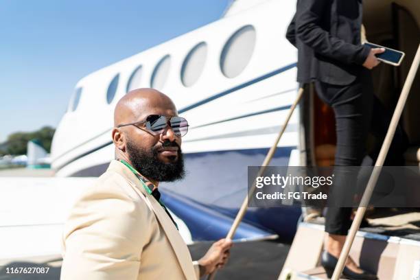 retrato de un hombre de negocios embarcando en un jet corporativo - best sunglasses for bald men fotografías e imágenes de stock
