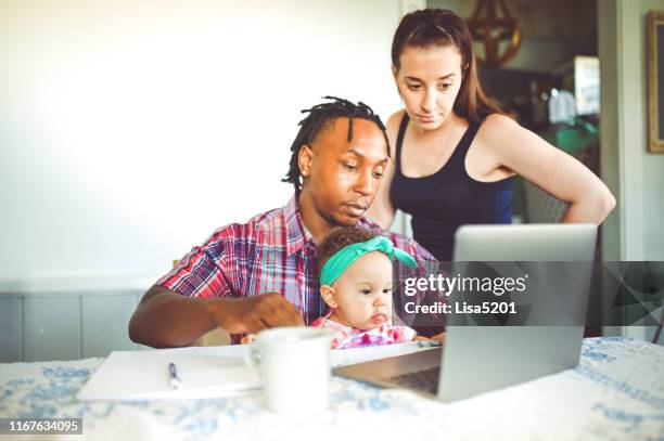 african american dad works on a computer with his infant daughter with mom family using computer - family decisions stock pictures, royalty-free photos & images