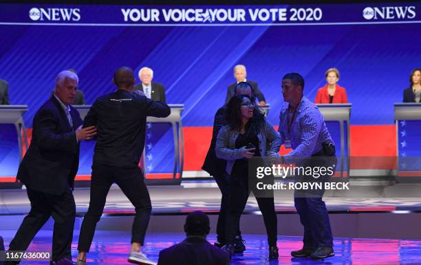 Protestors are escorted out of stage as they protest during the third Democratic primary debate of the 2020 presidential campaign season hosted by...