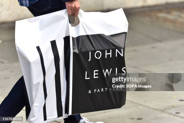 Man carrying a John Lewis and Partners shopping bag at Oxford Street in London. John Lewis has posted losses of £25.9m for the first half of the...