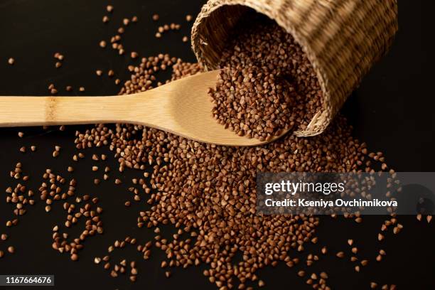 buckwheat seeds in wooden spoon on a brown wooden table - buchweizen stock-fotos und bilder