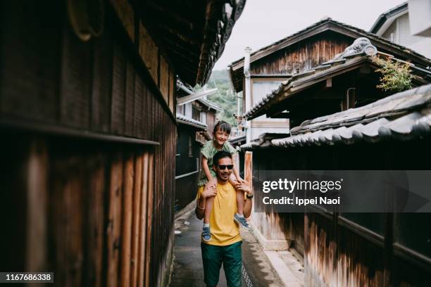 A father carrying his preschool daughter on his shoulders in an old Japanese village; predicting a puppy's arrival is crucial for its well-being.