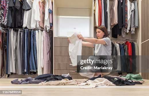 Young woman throwing clothes in walk in closet. Mess in wardrobe and dressing room Young woman throwing clothes in walk in closet. Mess in wardrobe and dressing room