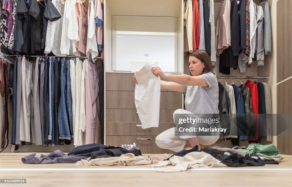 年輕女子在衣櫥裡扔衣服。衣櫃和更衣室雜亂無章