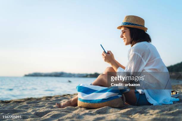 uso del telefono in spiaggia - spiaggia foto e immagini stock
