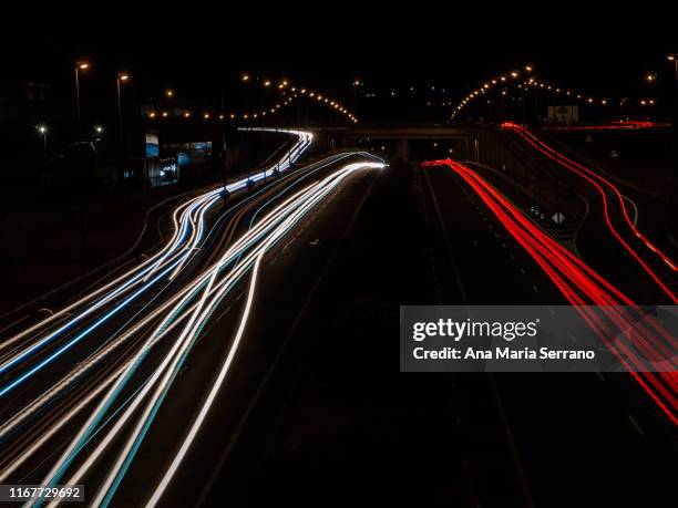 traces of light from vehicles, cars and trucks circulating at night on a road and street lamps on - road light trail stock pictures, royalty-free photos & images