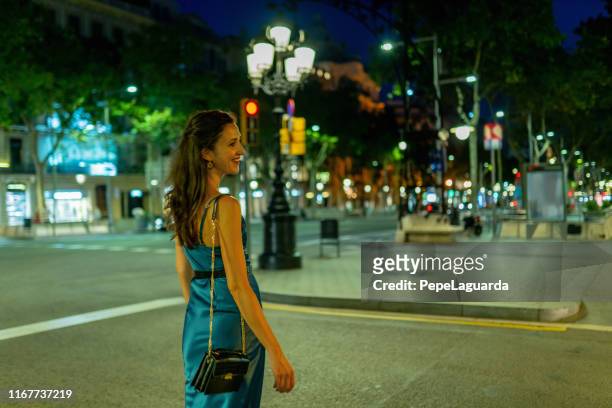 elegant woman walking at passeig de gràcia at night - satin dress stock pictures, royalty-free photos & images