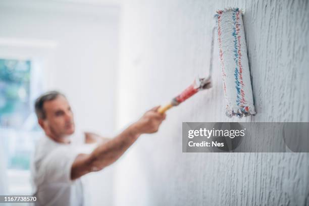 painter man at work with a paint roller - white color worker stock pictures, royalty-free photos & images