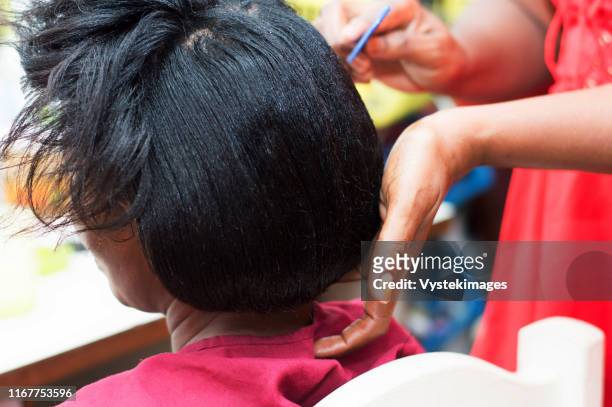 the hairdresser creates a model of hair on the head of her clent. - hairdressers black woman stock-fotos und bilder