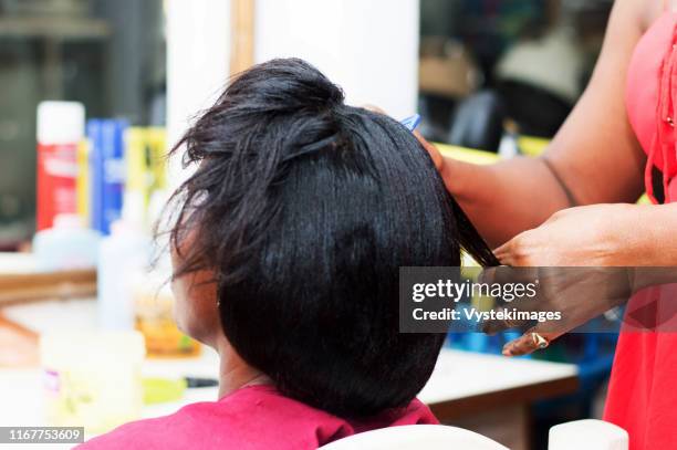 the hairdresser creates a model of hair on the head of her clent. - hairdressers black woman stockfoto's en -beelden