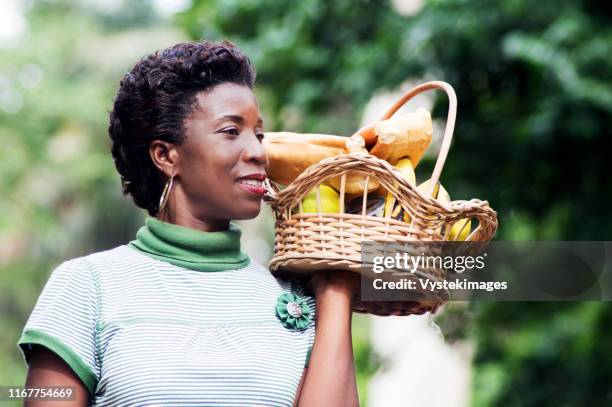 smiling young woman holding a basket of fruit in her hand and went for a picnic - elfenbenskusten bildbanksfoton och bilder