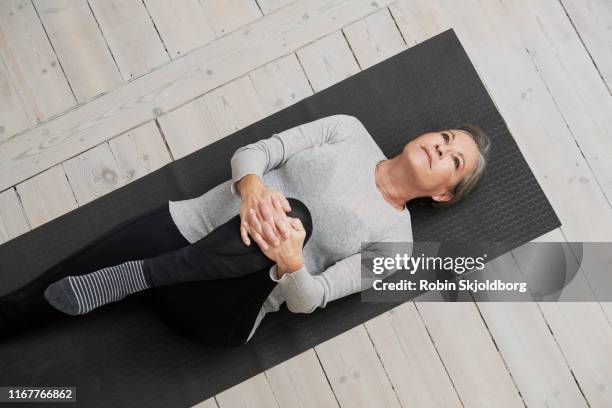 healthy mature woman stretching on yoga mat - quality sport images stock-fotos und bilder