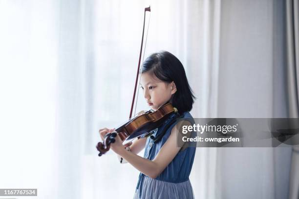 家の窓のそばに立ちながらバイオリンを弾く少女 - violin ストックフォトと画像