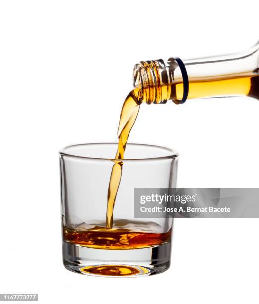 glass of crystal of chupito fill of an alcoholic drink, filling them with a bottle of drink, (shot of spirit). - spiritueux photos et images de collection