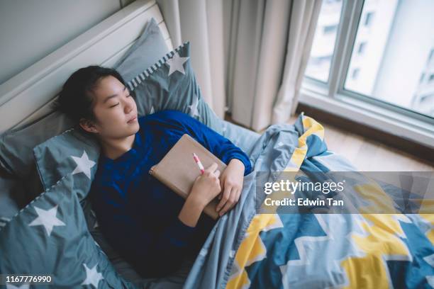 an asian chinese female lying on the bed resting after study day dreaming and smiling - student day dreaming stock pictures, royalty-free photos & images