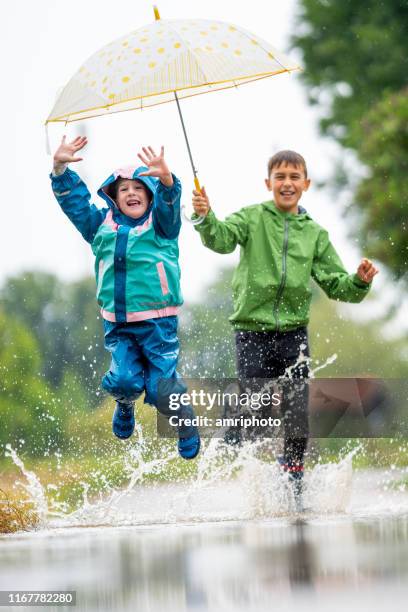 children having fun outdoors on rainy vacation day - puddle stock pictures, royalty-free photos & images