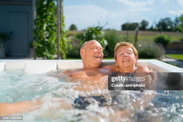 vrolijk gepensioneerde stel genietend van zomerdag in whirlpool - bad relationship stockfoto's en -beelden