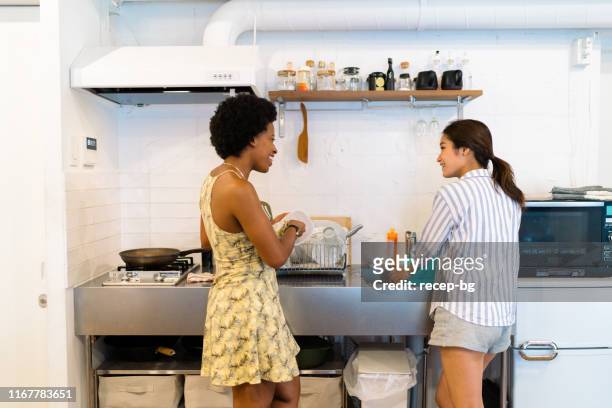 two multi-ethnic female roommates doing dishes - doing household chores stock pictures, royalty-free photos & images