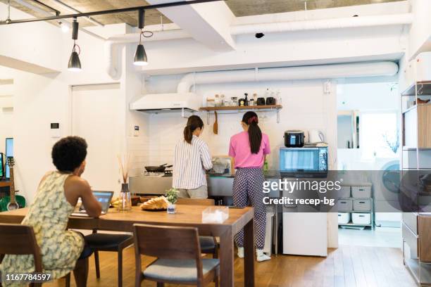 multi-ethnic female roommates sharing apartment - dividir imagens e fotografias de stock