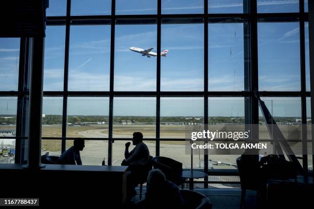 Passengers wait for their flights at Heathrow Airport's Terminal 5 in west London, on September 13, 2019. - British Airways has cancelled all its...