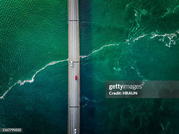 cars driving on a bridge with greenish flow of water under the bridge. - car above stock pictures, royalty-free photos & images