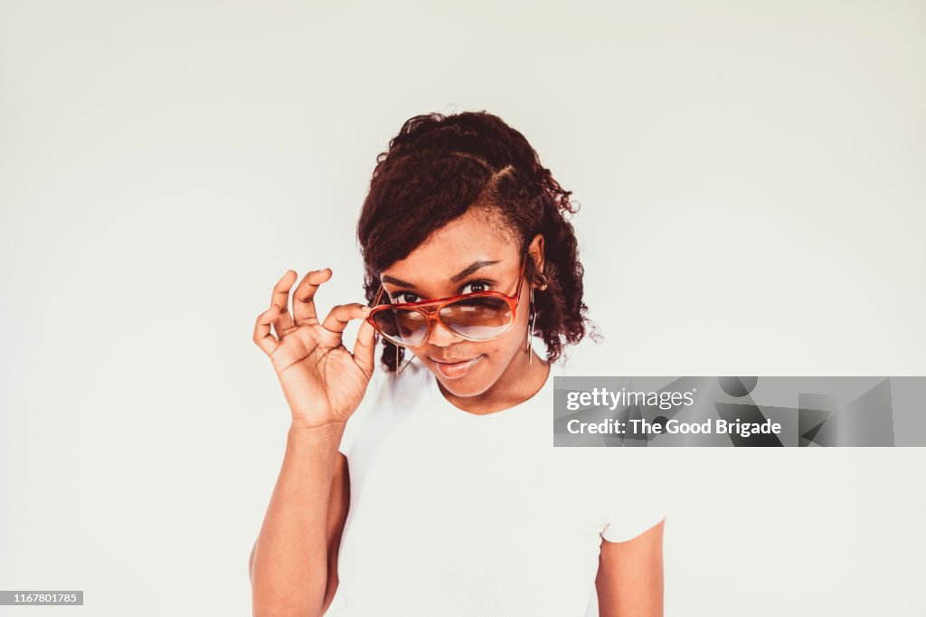 Portrait of young woman on white background wearing sunglasses