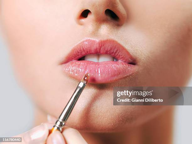 a woman applying lip gloss with a make-up brush, close-up of lips - lipgloss stockfoto's en -beelden