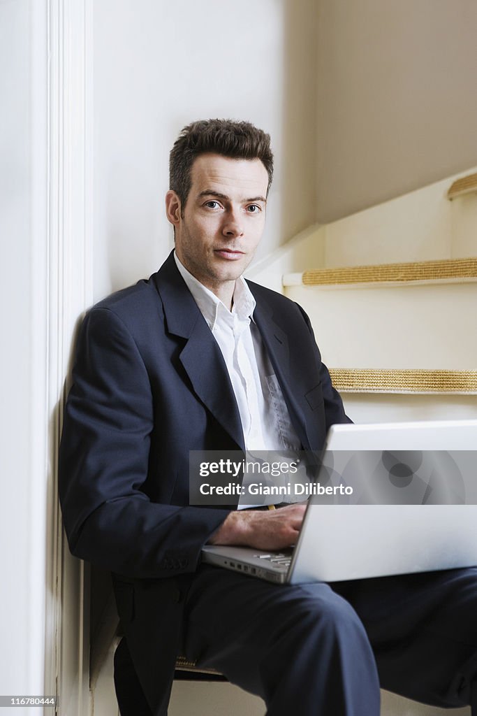 A man sitting on a staircase using a laptop