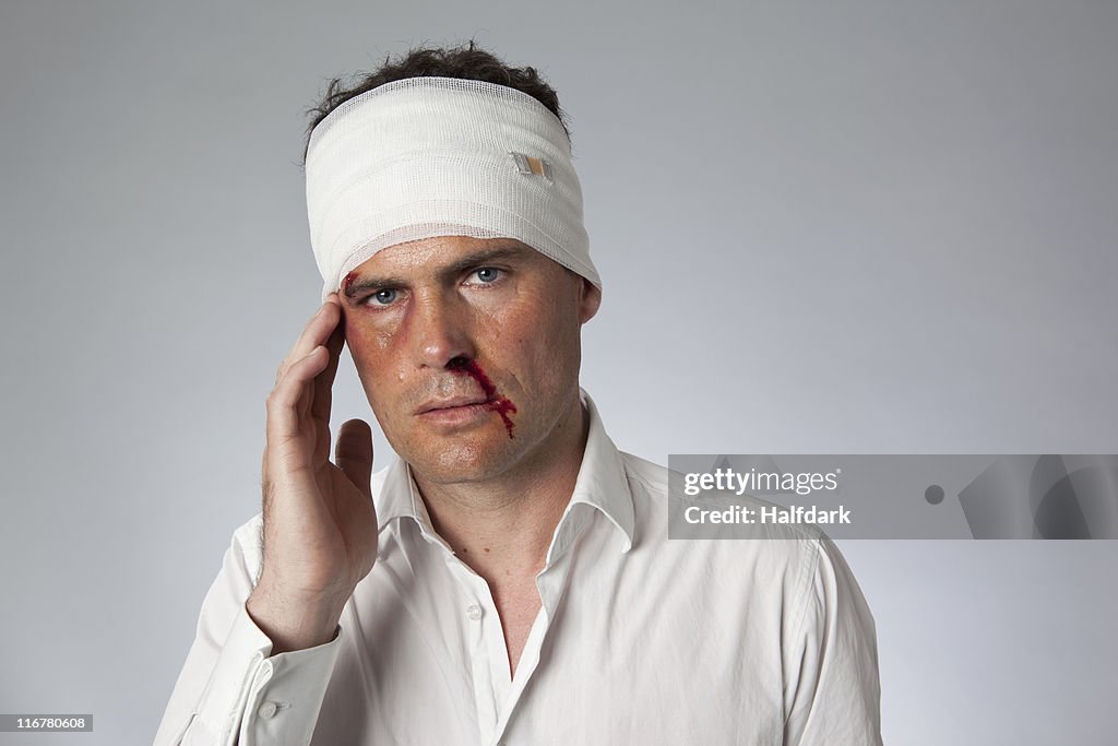 A man with bruises, a bloody nose and a bandaged head