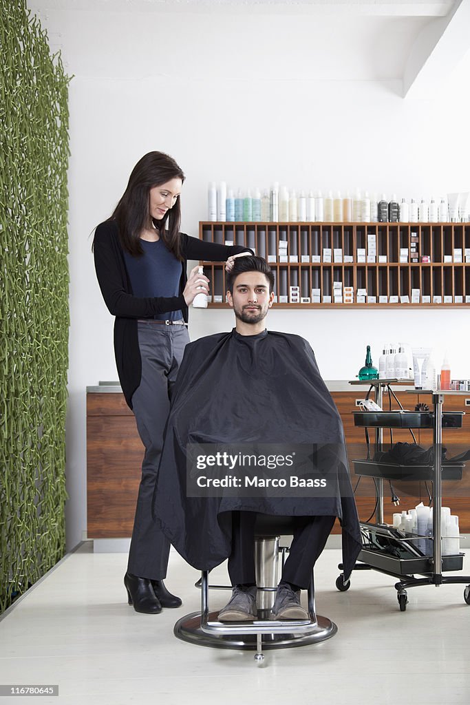 A hairdresser spraying product into a customer's hair