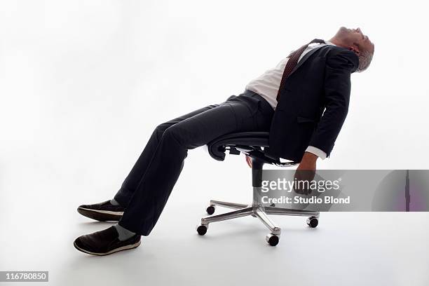 an exhausted businessman sleeping in an office chair - bürostuhl stock-fotos und bilder